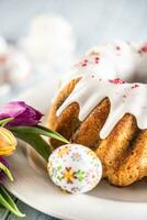 Festive easter marble cake with icing sugar hand-decorated eggs and spring tulips photo