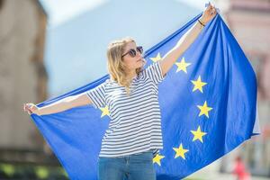 atractivo contento joven niña con el bandera de el europeo Unión foto