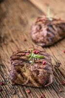 Grilled beef steak with rosemary, salt and pepper on old cutting board. Beef tenderloin steak. photo