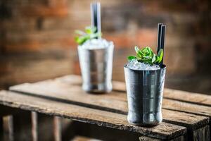 Mint julep cocktail alcoholic drink on wooden board in pub or restaurant photo