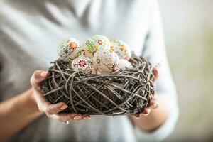 Birds nest full of colorful easter eggs held in womens hands photo