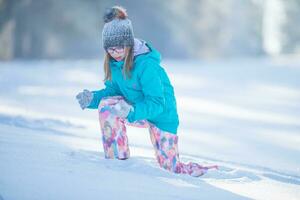 Happy young Pre-Teen girl in warm clothing  playing with snow photo