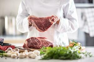 cocinero participación un grande cortar de crudo Cerdo o carne de vaca carne en un profesional cocina foto