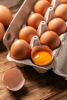 Chicken eggs in a cardboard box and yolk in shell. photo