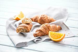 Fresco mantecoso cruasanes con dulce naranjas en cocina servilleta foto