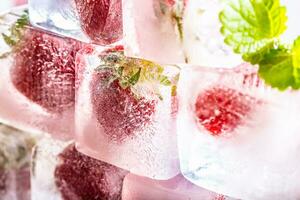 Fresh strawberries frozen in ice blocks with melissa leaves photo