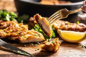 Viennese chicken steak on a fork. Traditional Austrian and German dish of chicken meat and breadcrumbs photo