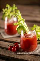 Bloody or virgin mary cocktail served in a cup with celery sticks and cherry tomatoes photo