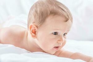 Portrait of cute toddler boy lying on bed. Newborn child in bedroom photo