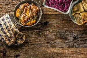 Roasted duck legs in pan with oranges herbs red cabbage and potato pankaces photo
