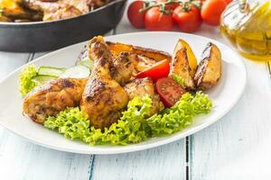 Roasted chicken legs with lettuce salad and tomatoes photo