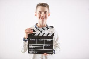 Young boy on an isolated white background holds an open movie clapper board photo