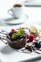 Brownies with ice cream and fruit, mint and chocolate decoration with an espresso on a cafe table photo