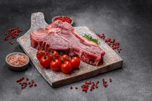 Raw fresh juicy beef t-bone steak with salt, spices and herbs photo