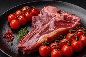 Raw fresh juicy beef t-bone steak with salt, spices and herbs photo