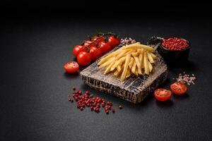 Delicious crispy french fries with salt and spices on a textured concrete background photo