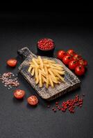 Delicious crispy french fries with salt and spices on a textured concrete background photo