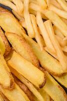 delicioso crujiente francés papas fritas con sal y especias en un texturizado hormigón antecedentes foto