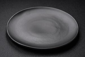 Empty black plate over dark stone background with copy space photo