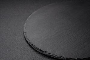 Empty black plate over dark stone background with copy space photo