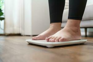 Fat diet and scale feet standing on electronic scales for weight control. Measurement instrument in kilogram for a diet control. photo