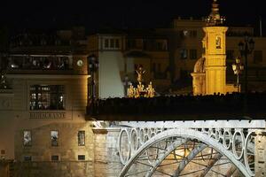 Cristo el cachorro cruce triana puente con un procesión de fiel en el camino a el capilla de carmen en su barrio foto