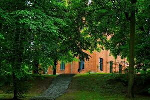 Polish historic brick palace in Rzucewo surrounded by summer greenery photo