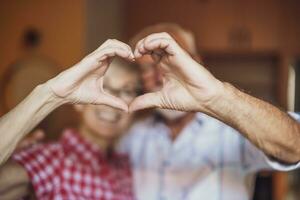 Happy senior couple is embracing and making heart shape with their hands. photo