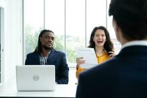 Job interview concept. Diverse hr team doing job interview with a man in business office. Happy business people working in office. Hiring and recruitment concept. Positive business office meeting. photo