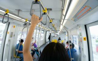 Woman hand firm grip safety handrail in elevated monorail train. Mass transit system in modern city. Inside of electric train. Tourist travel by city sky train. Public transportation. Urban transport. photo