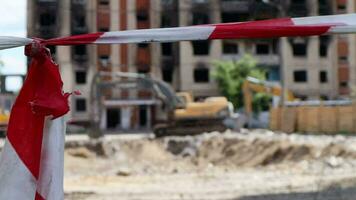 démolition de une gratte-ciel bâtiment. le effondrer de une Résidentiel bâtiment. construction travail sur le démolition de gratte-ciel appartements. clôture fabriqué de rouge et blanc avertissement enregistrer. video