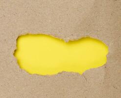 Torn edges of brown paper on a yellow background, space for writing photo