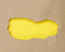 Torn edges of brown paper on a yellow background, space for writing photo