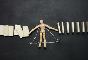 Wooden puppet toy holding a falling domino photo