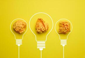 Crumpled balls of paper inside an electric lamp on a yellow background. Concept of new ideas, brainstorming photo