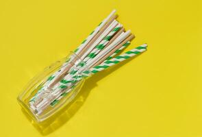 Paper tubes in a transparent glass on a yellow background, top view photo