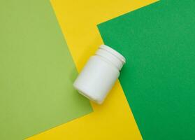 White plastic jar for pills, cream and medicines on a green background. Container for substances, top view photo