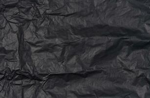 Crumpled sheet of black parchment paper, abstract background photo