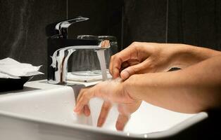 Man's hand is pouring in the sink in one of the luxury bathrooms on the property. photo