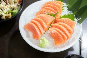 Fresco rebanado salmón o salmón sashimi con en blanco cuenco conjunto en mesa, japonés alimento. foto