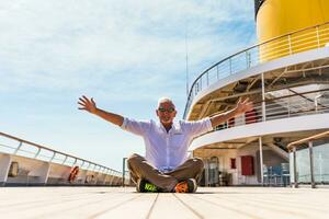 happy handsome middle aged man posing sitting on the deck of a cruise ship photo