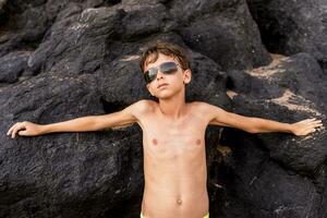 funny portrait of young shirtless man wearing sunglasses in an exotic beach photo