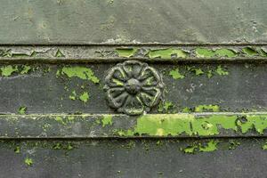 emblem in the shape of a flower on a rusty and scratched gray metal panel photo