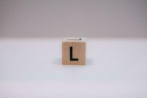 Wooden block written L with a white background, education concept, close up. photo