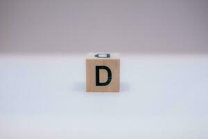 Wooden block written D with a white background, education concept, close up. photo