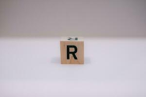 Wooden block written R with a white background, education concept, close up. photo