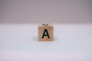 Wooden block written A with a white background, education concept, close up. photo