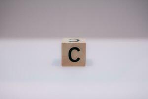 Wooden block written C with a white background, education concept, close up. photo