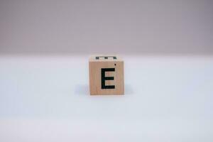Wooden block written E with a white background, education concept, close up. photo