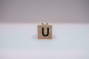 Wooden block written U with a white background, education concept, close up. photo